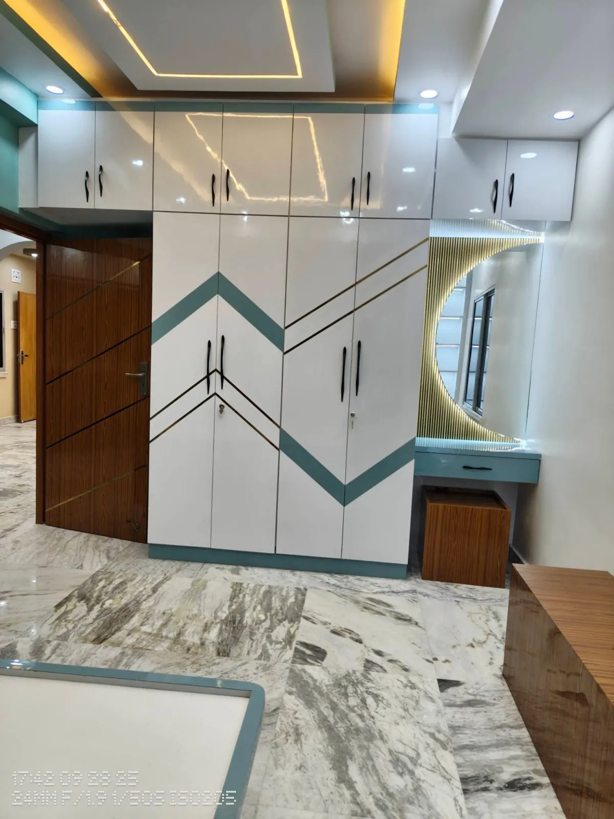 Contemporary living room design in Sarsuna, Kolkata, featuring exposed brick storage shelves, ambient warm LED ceiling lights, concrete accent wall, and cozy cream sofa setup by Agnimitra Interior Design.